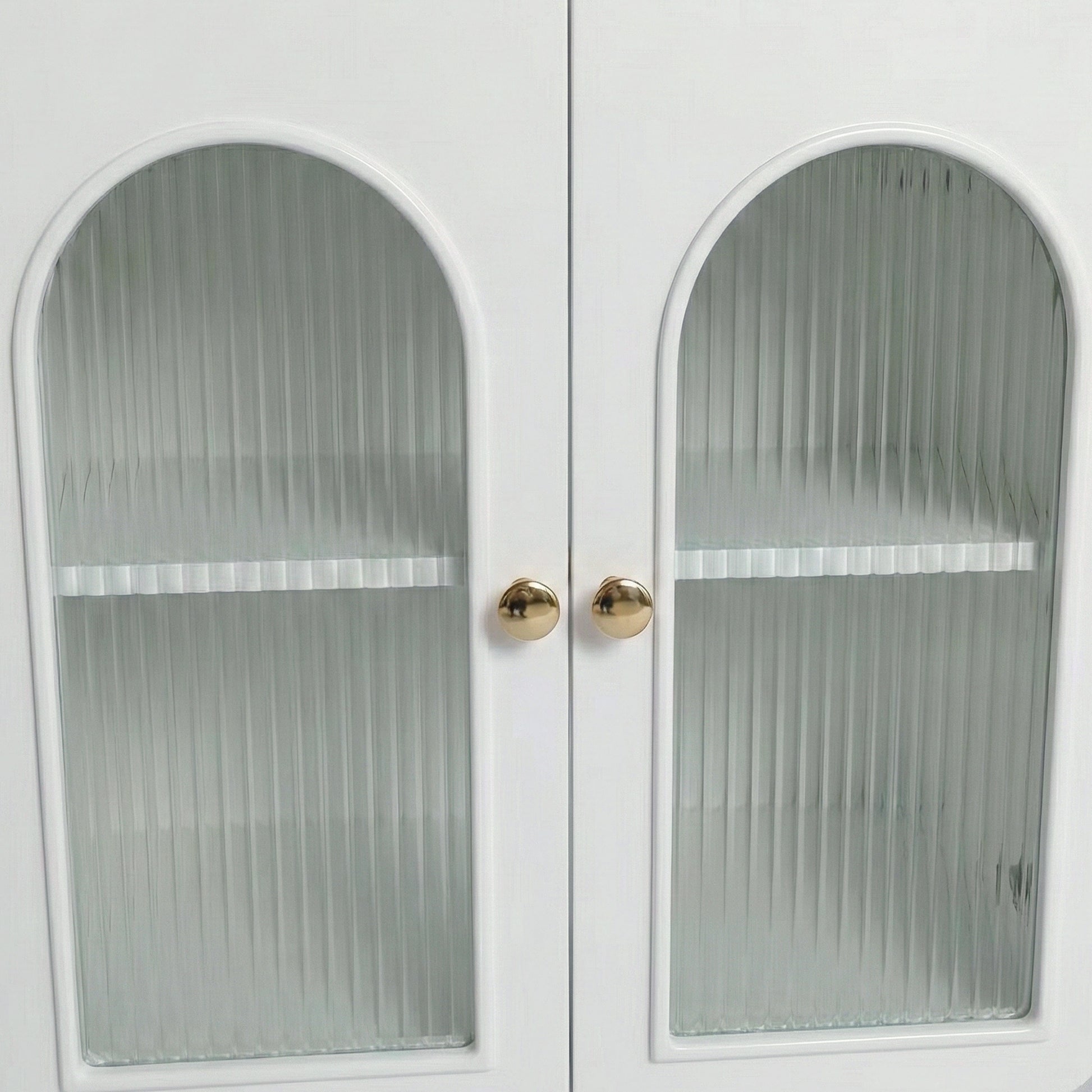Close-up of white cabinet doors with arched ribbed glass panels