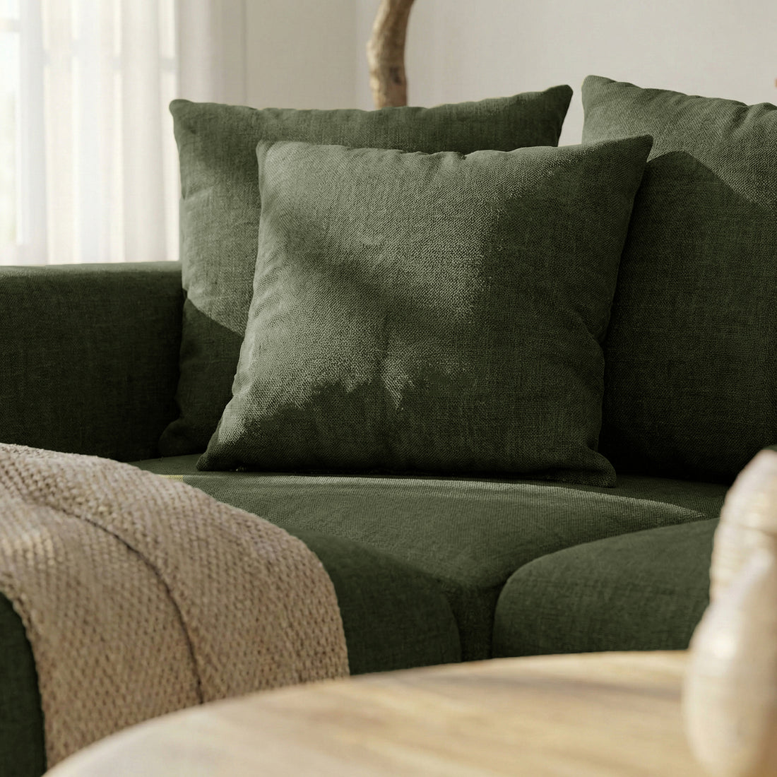 Corner of dark green sofa with throw in cozy living room