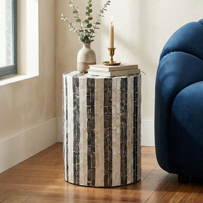 Cylindrical side table next to a blue sofa in a modern living room setting