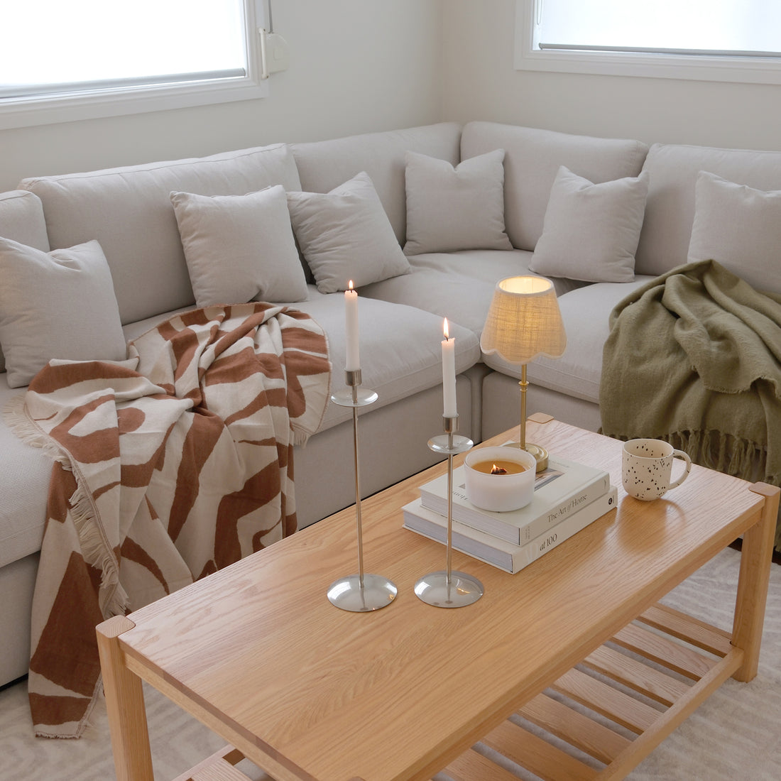 Light wood coffee table styled with candles, books, and decor in a living room.