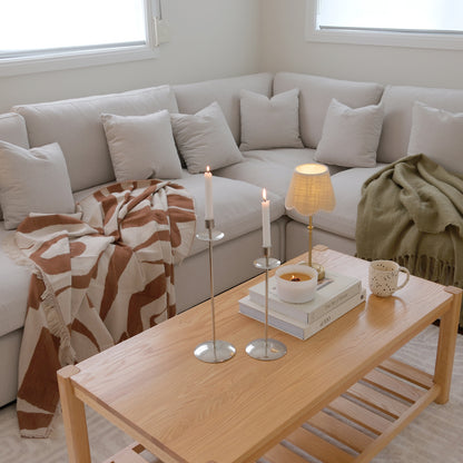 Light wood coffee table styled with candles, books, and decor in a living room.