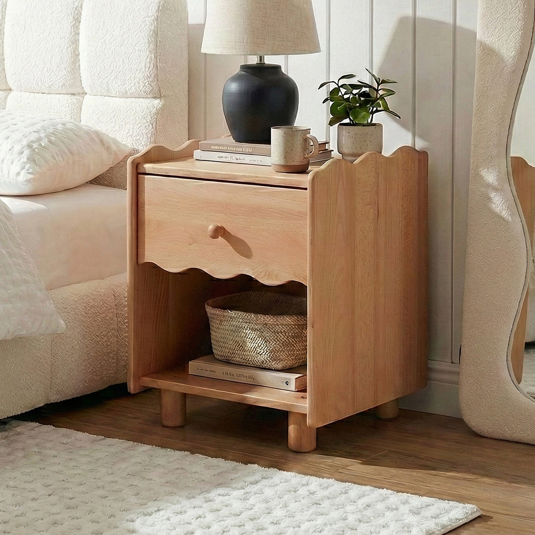 Wooden nightstand styled in a cozy bedroom with a lamp, books, and décor