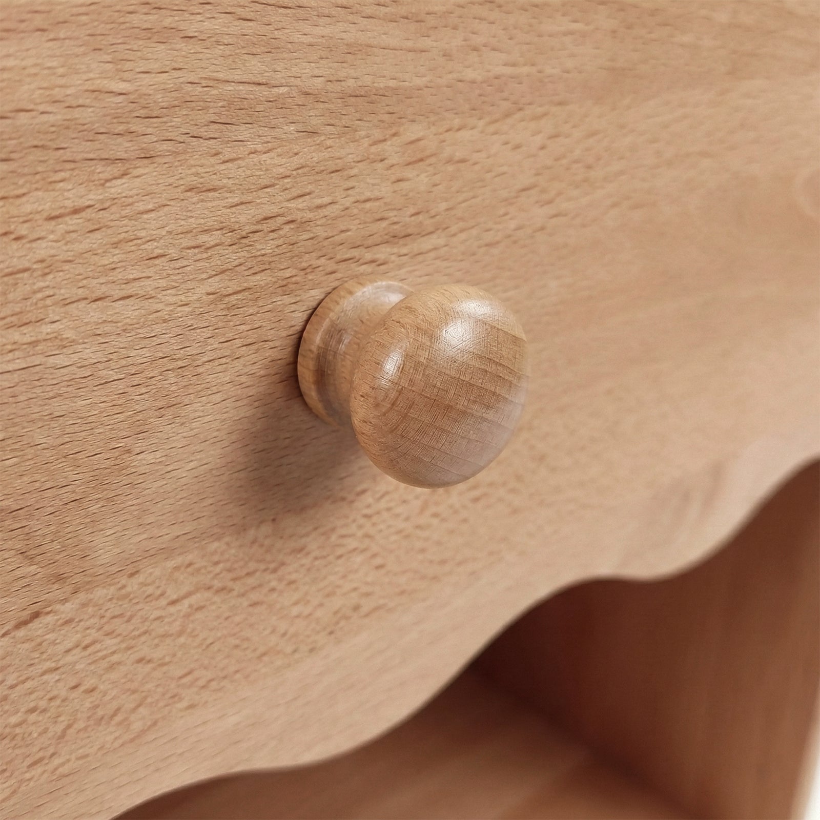 Close-up of round wooden drawer knob on wood grain background