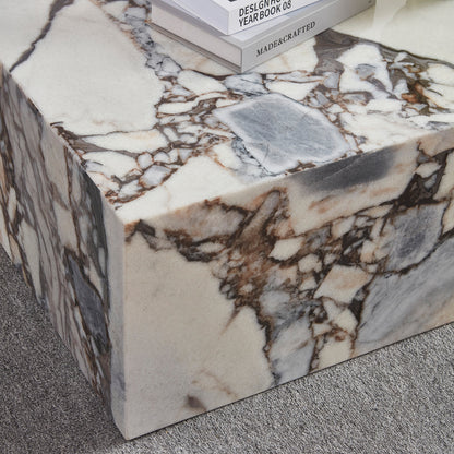 The Solene 100cm Coffee Table in Blue Galaxy features a white marble surface with striking brown and gray veining, topped with hardcover books, set on a low-pile grey carpet.