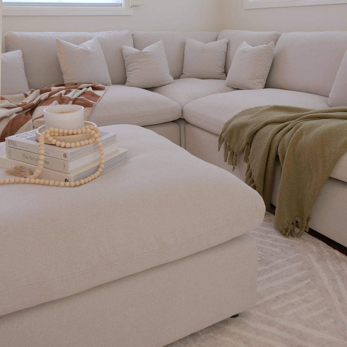 Light-colored sectional sofa with ottoman in a warm living room setting