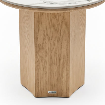 Partial view of a round table with a geometric wood base and marble top on a white background.