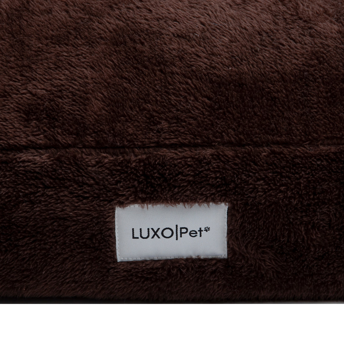 Close-up of plush brown fabric seam and Luxo|Pet label on white background