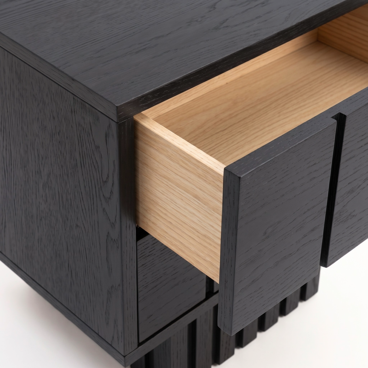 Partial view of a black wooden nightstand with an open drawer on white background