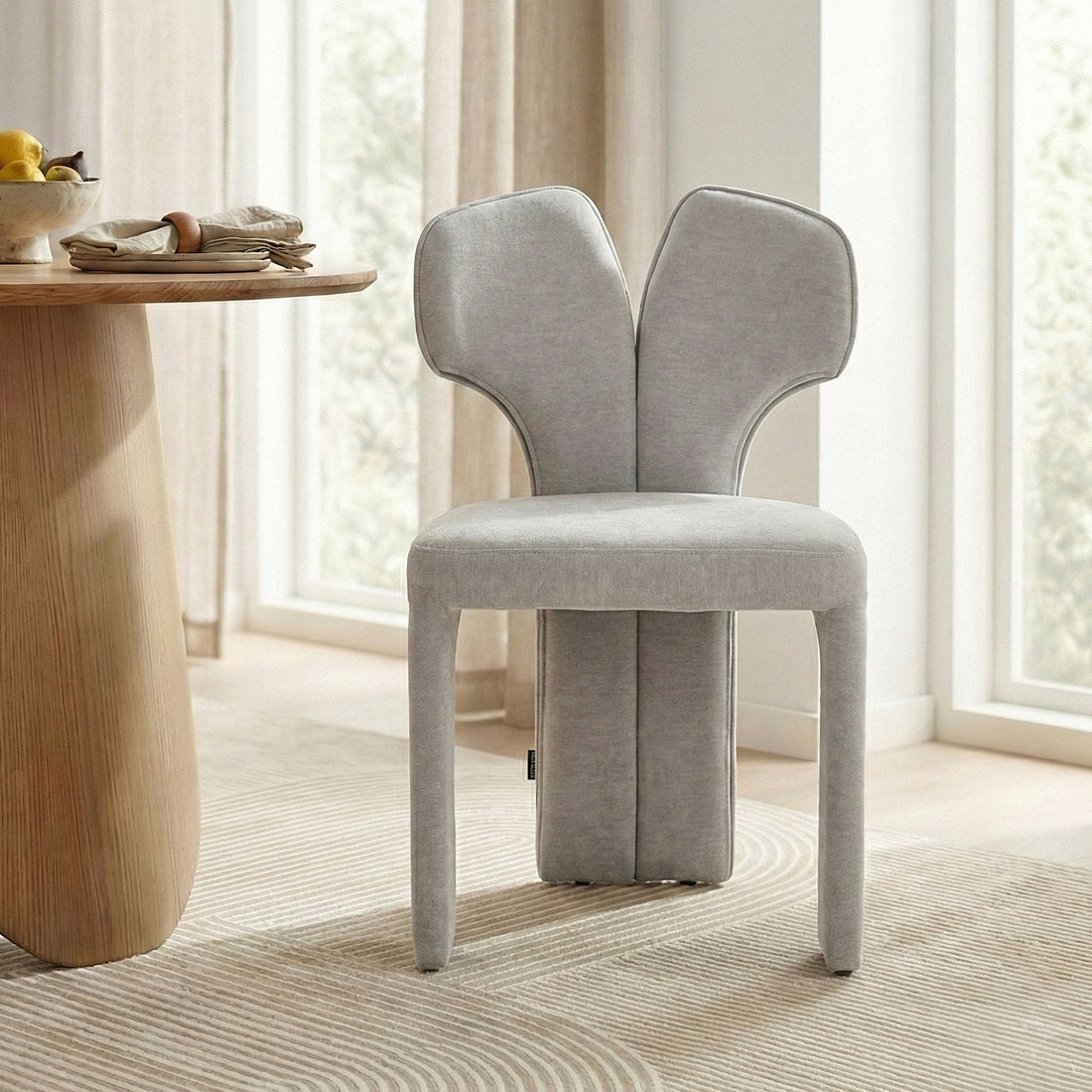 Light gray upholstered chair next to a wooden dining table in bright modern room