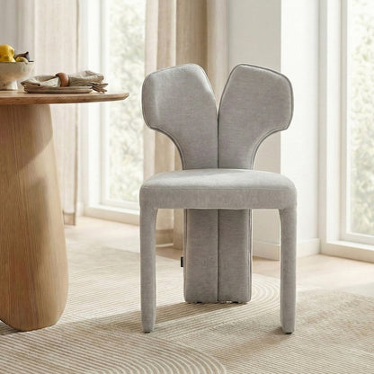 Light gray upholstered chair next to a wooden dining table in bright modern room