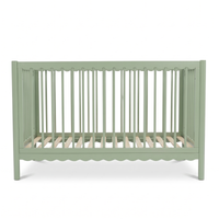Sage green baby crib on white background highlighting scalloped bottom detail