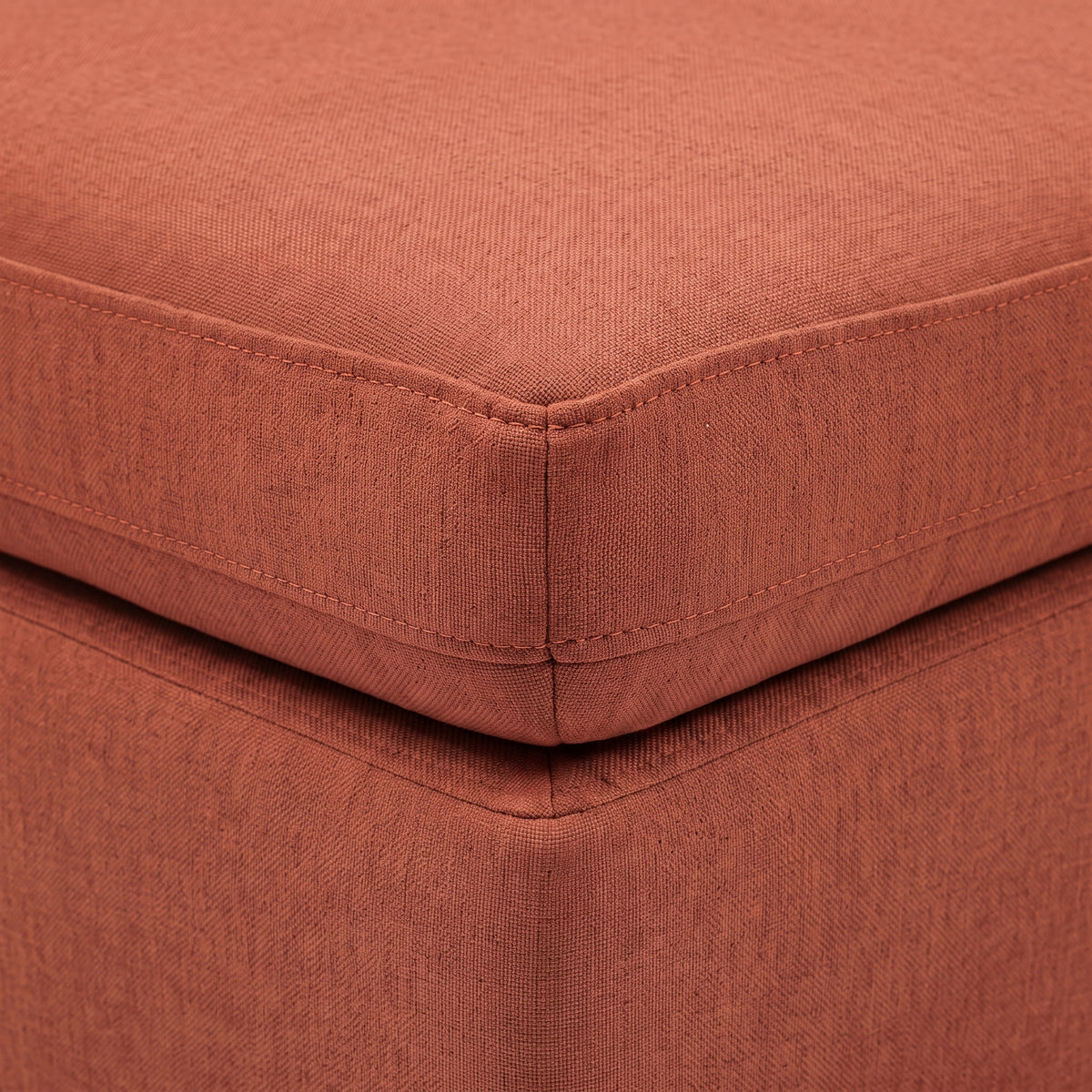 Close-up of terracotta upholstered cushion corner and piping