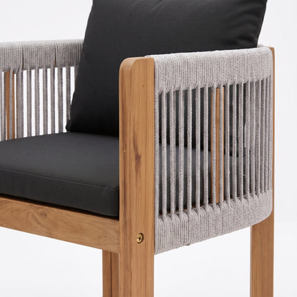 Close-up of a wooden chair with rope sides and black cushions on a white background