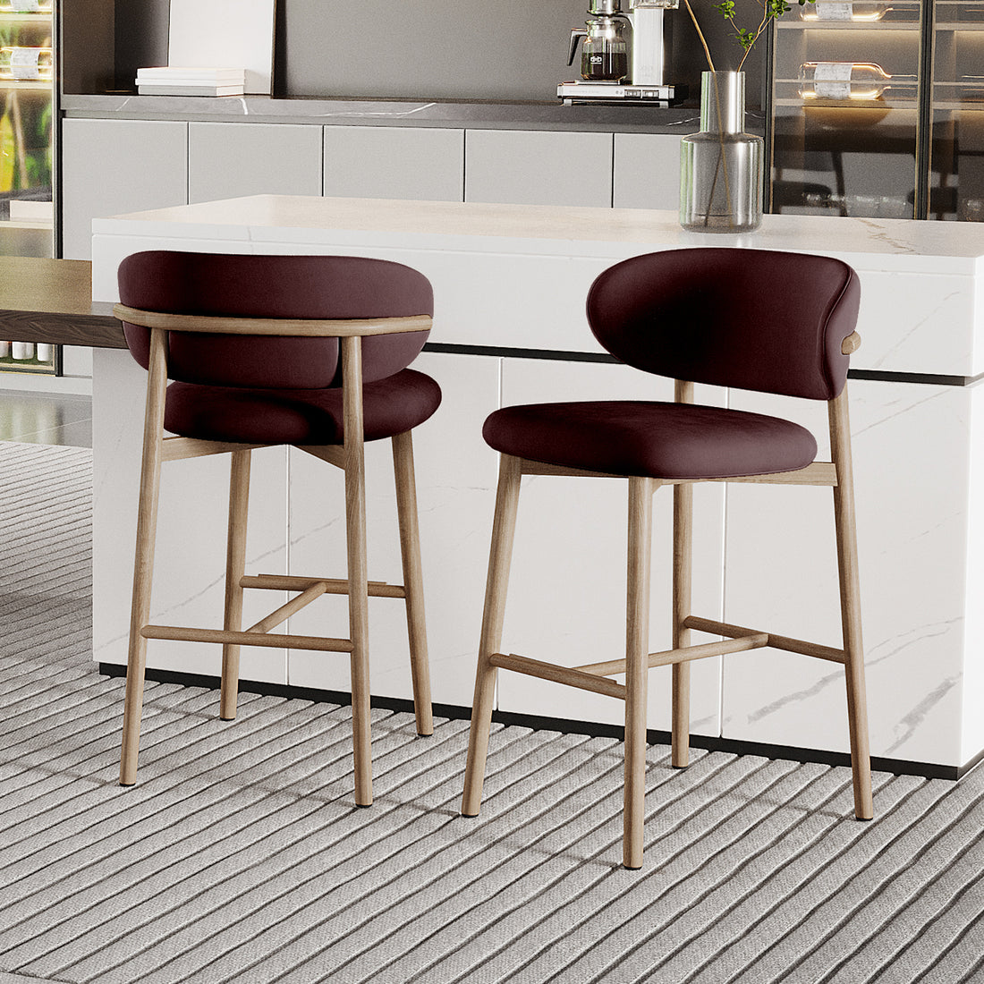 Audrey Fabric Upholstered Barstool Set of 2 in Dark Plum, featuring backless design, light wood legs, and plush seats. Positioned at a white marble-effect counter with a coffee machine and vase on top.