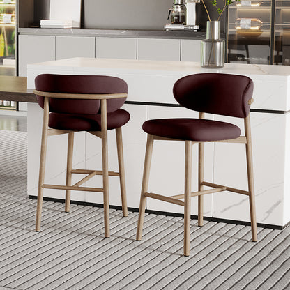 Audrey Fabric Upholstered Barstool Set of 2 in Dark Plum, featuring backless design, light wood legs, and plush seats. Positioned at a white marble-effect counter with a coffee machine and vase on top.