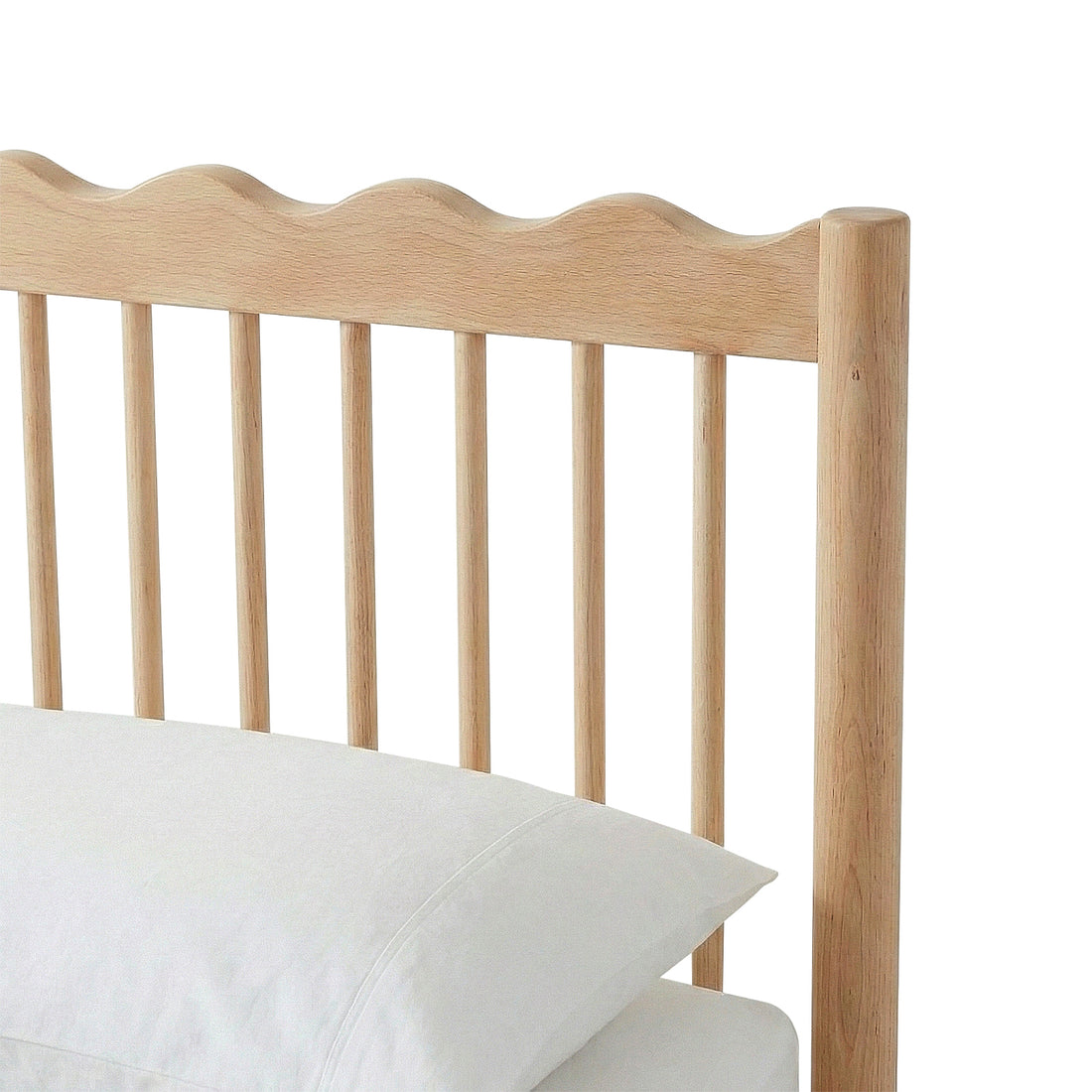 Close-up of wooden headboard with wavy top edge and vertical slats