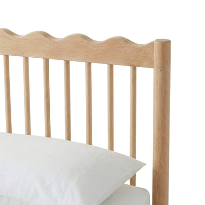 Close-up of wooden headboard with wavy top edge and vertical slats
