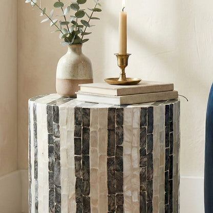 Close crop of tiled side table with vase, books, and candle in a home corner