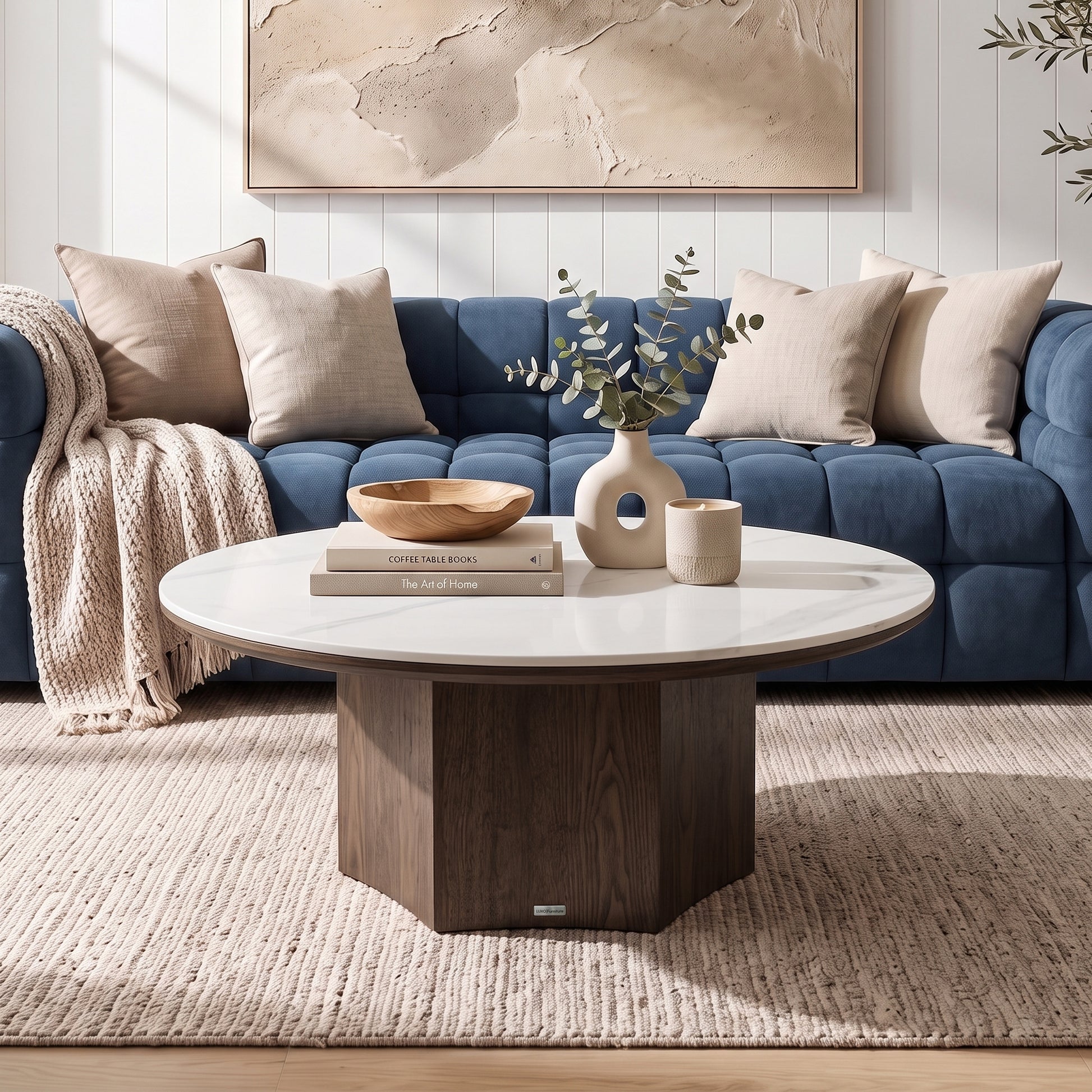 Round coffee table styled in a modern living room with a blue tufted sofa and decor.