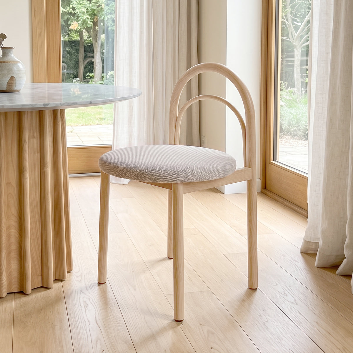 Modern chair placed in a bright room beside a table with natural light.