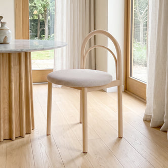 Modern chair placed in a bright room beside a table with natural light.