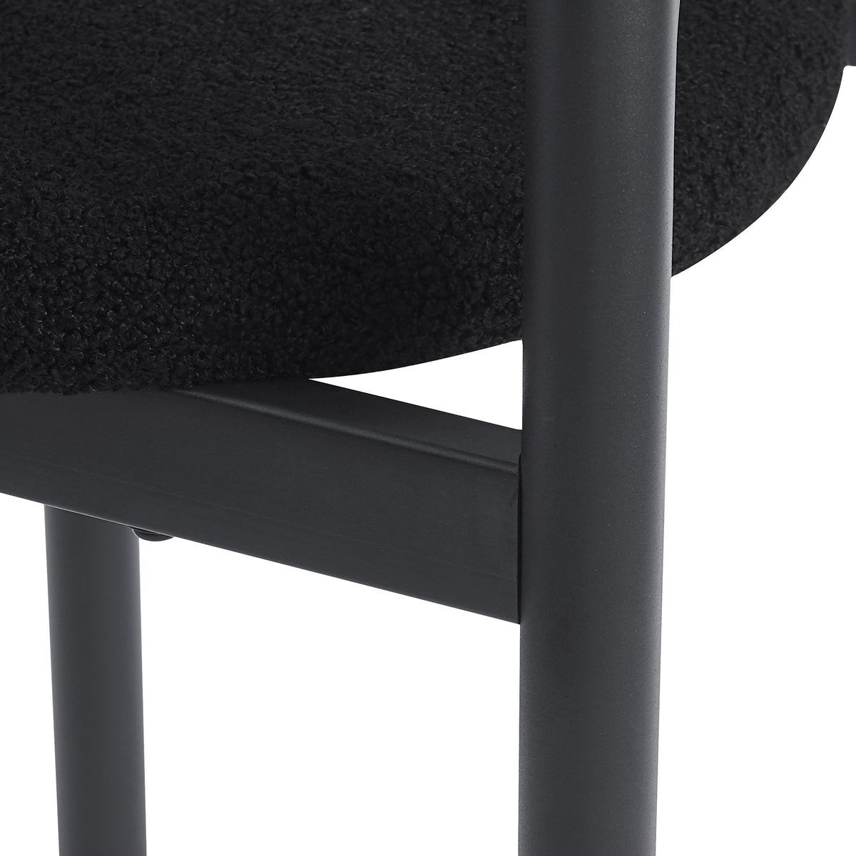 Close-up of black upholstered seat and metal legs on a white background