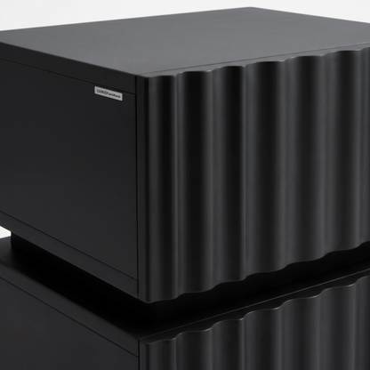 Partial view of a black textured cabinet with a wavy front on a white background.