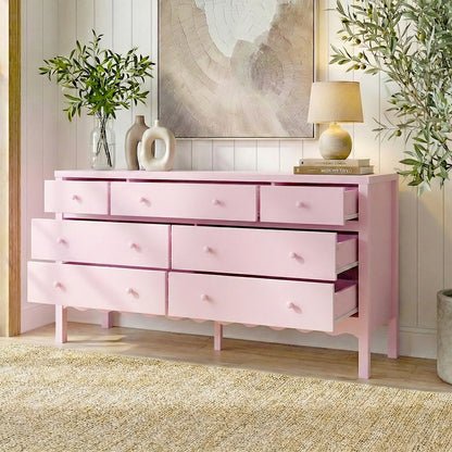 Pink dresser with nine drawers styled with vases, lamp, and plants