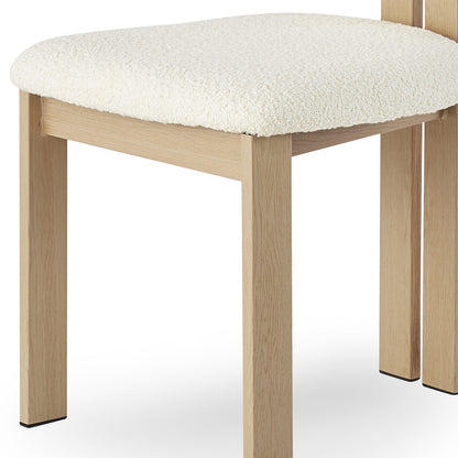 Close-up of the Haleo Curved Boucle Dining Chair Set of 2 in Cream White, highlighting its four straight, light-wood legs and padded, off-white upholstered seat, embodying modern comfort and style.