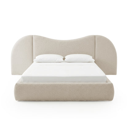 Front view of beige upholstered bed with pillows on white background