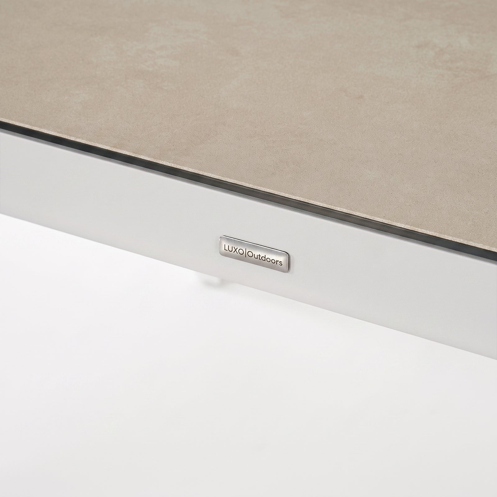 Close-up of the edge of a rectangular tabletop with a brand tag on a white background.