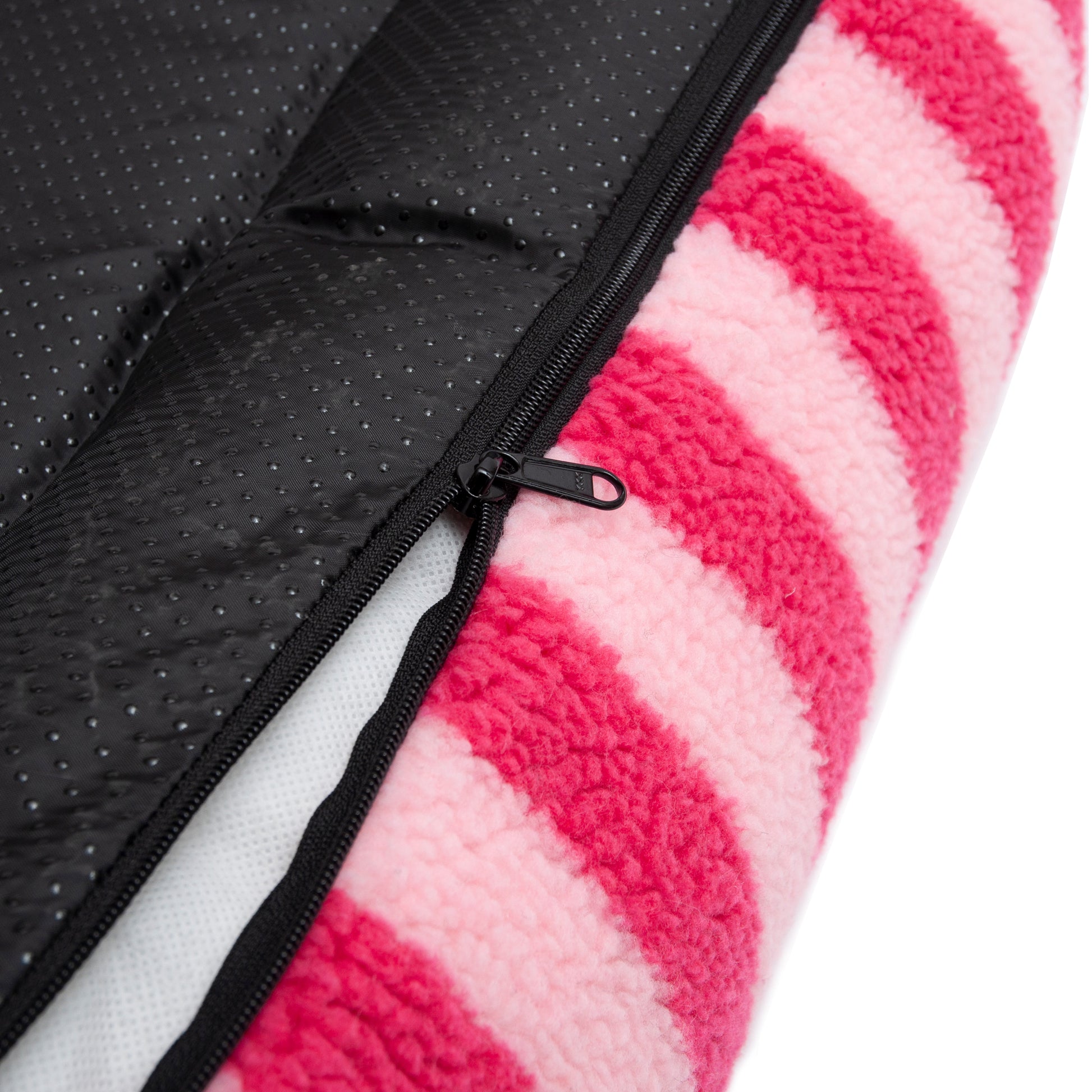 Extreme close-up of pink striped plush fabric and black zipper seam on a white background