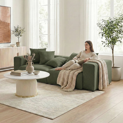 Woman seated on dark green sectional sofa in a modern living room