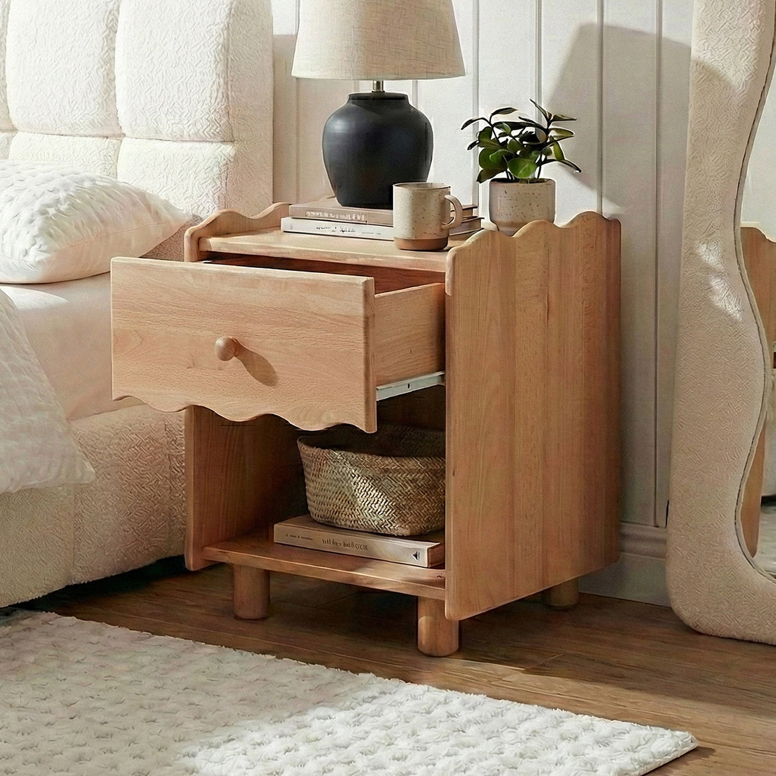 Wooden nightstand in bedroom beside bed with lamp and décor items