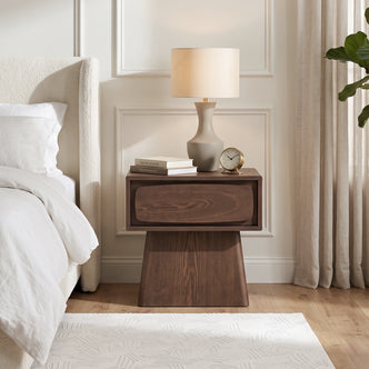 Wooden nightstand styled beside a bed in a bedroom