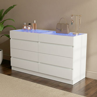 White dresser with six drawers in a styled room setting with decorative items against beige wall