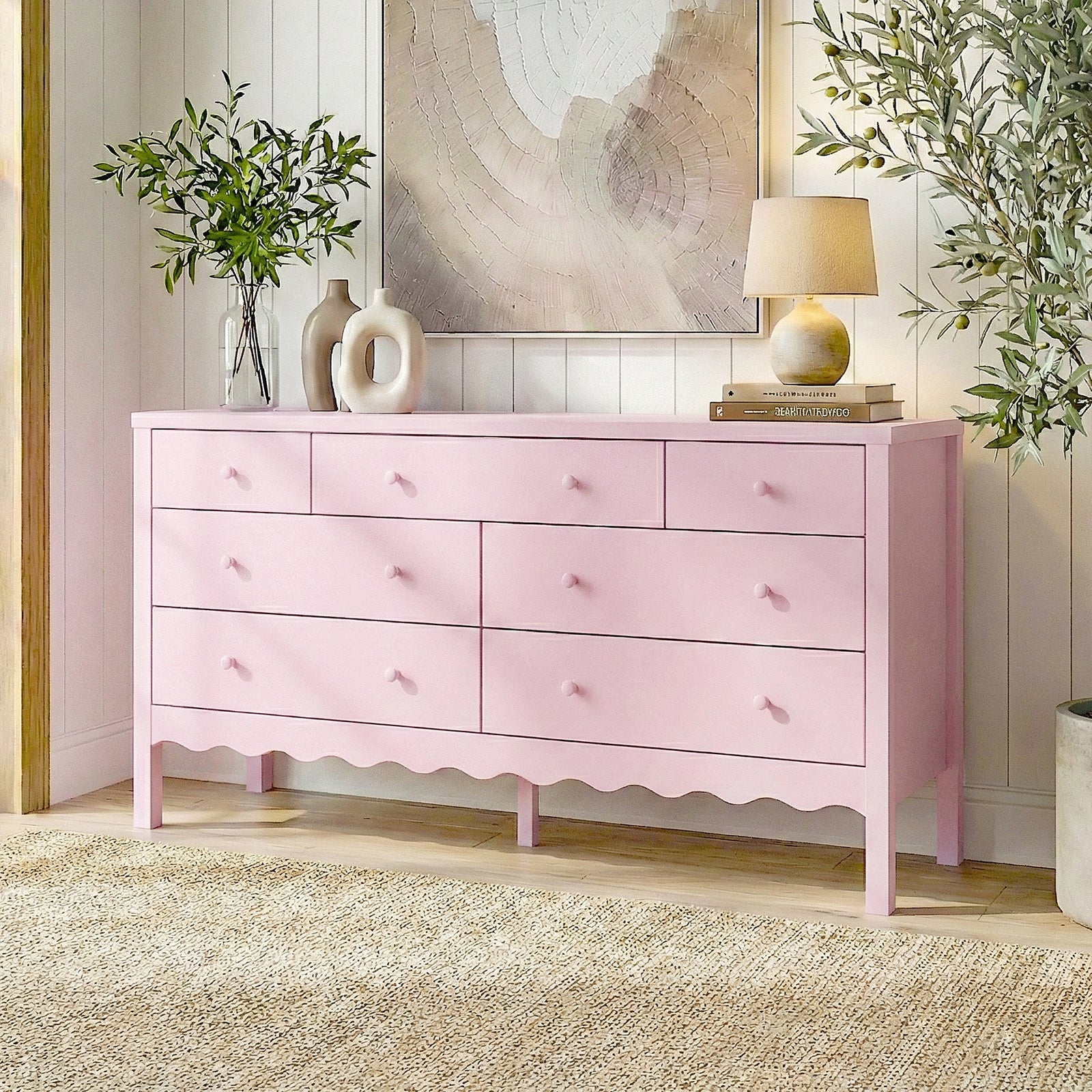 Pink dresser in a decorated room with rug, plants, and wall art