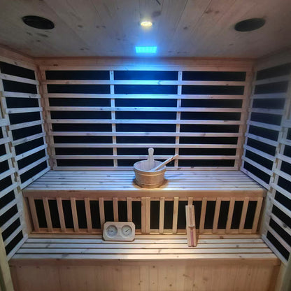 Luxo Kiima 6 Person Hybrid Finnish Outdoor Sauna in Natural features wooden benches, black heater panels, a water bucket, a thermometer/hygrometer, ceiling light, and speakers, creating a relaxing retreat.