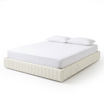 Modern upholstered platform bed with white mattress and pillows on white background