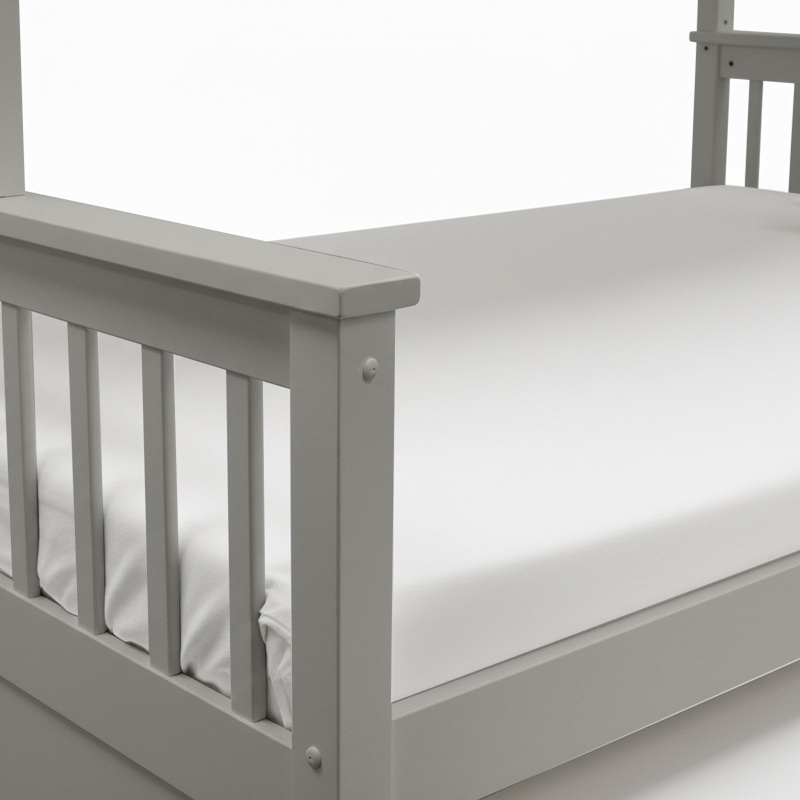 Close-up of grey bed frame corner and side railings with mattress edge on white background