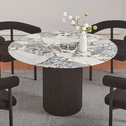 Gracie 120cm Round Marble Dining Table in Black with a veined marble top and fluted base, surrounded by black upholstered chairs, accented with a vase and glasses on a grey rug.