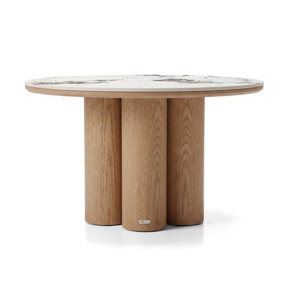 Round dining table with a light wood cylindrical base and marble-look top on a white background