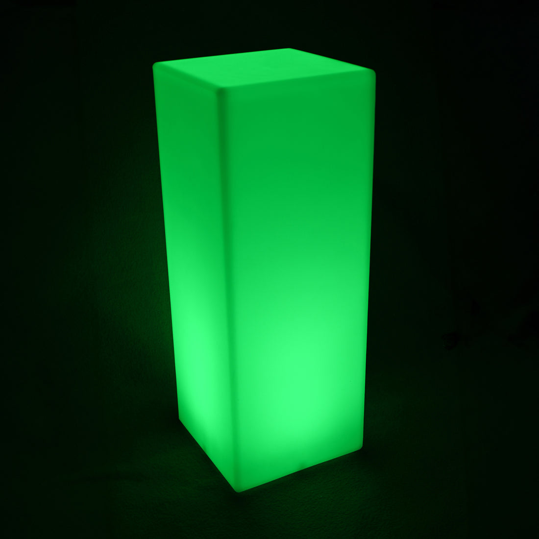 Colour Changing LED Column Light Indoor & Outdoor, a tall, glowing green rectangular prism, emits a bright light, perfect for creating ambience in both indoor and outdoor settings against a dark backdrop.