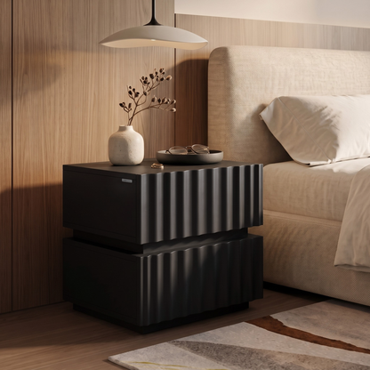 Modern black ribbed nightstand styled beside a bed in a bedroom setting.
