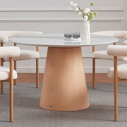 Dina 120cm Round Marble Dining Table in Carrara Natural with a pale gray marble top on an oak base, surrounded by four bouclé-upholstered chairs, accented by a vase and tray.
