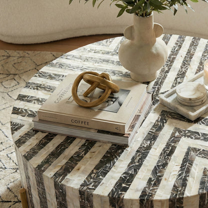 Round coffee table with geometric pattern in a room setting, partially cropped at bottom