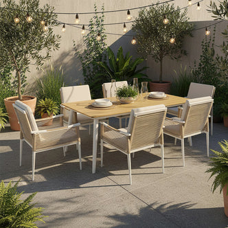 Casara 7 Piece Outdoor Dining Set featuring a light-wood table and six rope-wrapped armchairs with cushions, surrounded by potted plants and string lights, creating a serene al fresco dining ambiance.