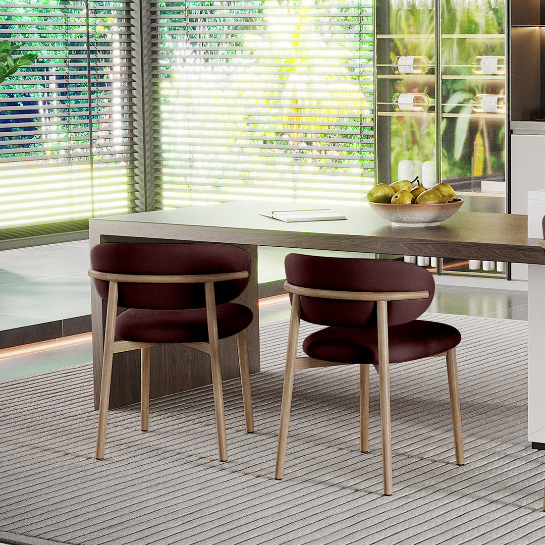 Audrey Fabric Dining Chair Set of 2 in Dark Plum, featuring light wood frames, rounded burgundy seats, and backrests, placed at a wooden table with a bowl of green pears nearby.