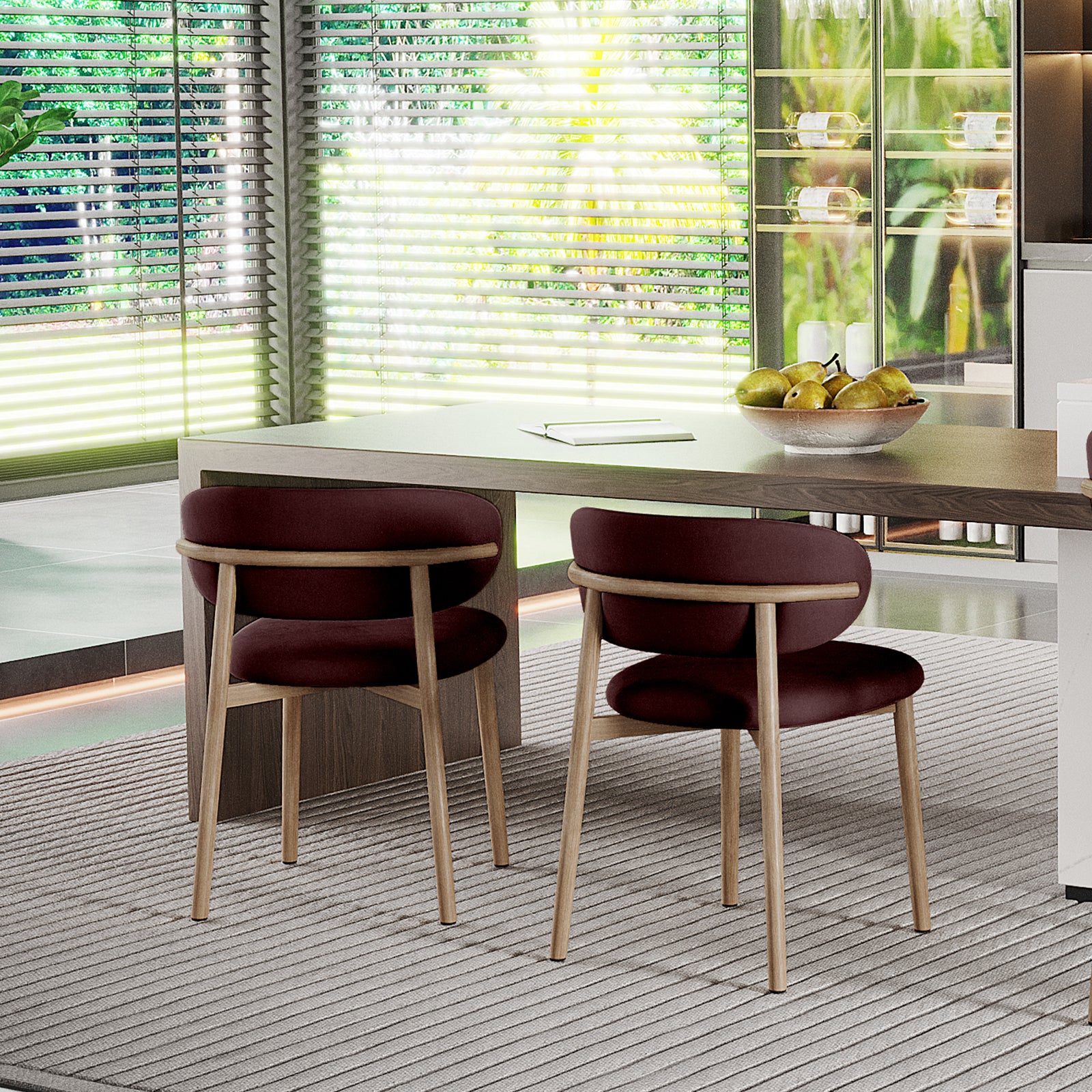 Audrey Fabric Dining Chair Set of 2 in Dark Plum, featuring light wood frames, rounded burgundy seats, and backrests, placed at a wooden table with a bowl of green pears nearby.