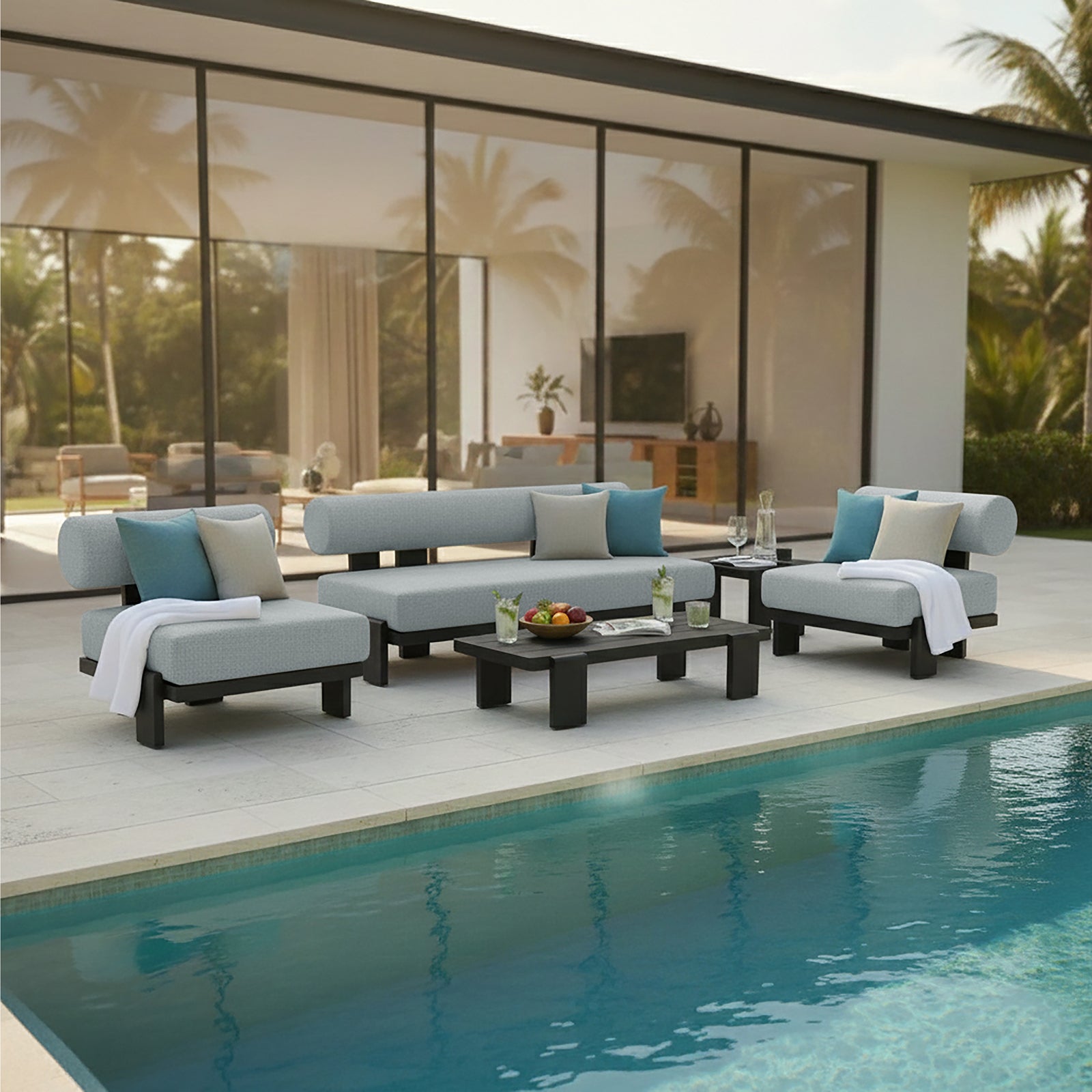 Modica 5 Seater Aluminium Outdoor Sofa Set in Black & Grey features light grey cushions on a sleek black aluminium frame, arranged poolside with a low coffee table topped with fruit and drinks.